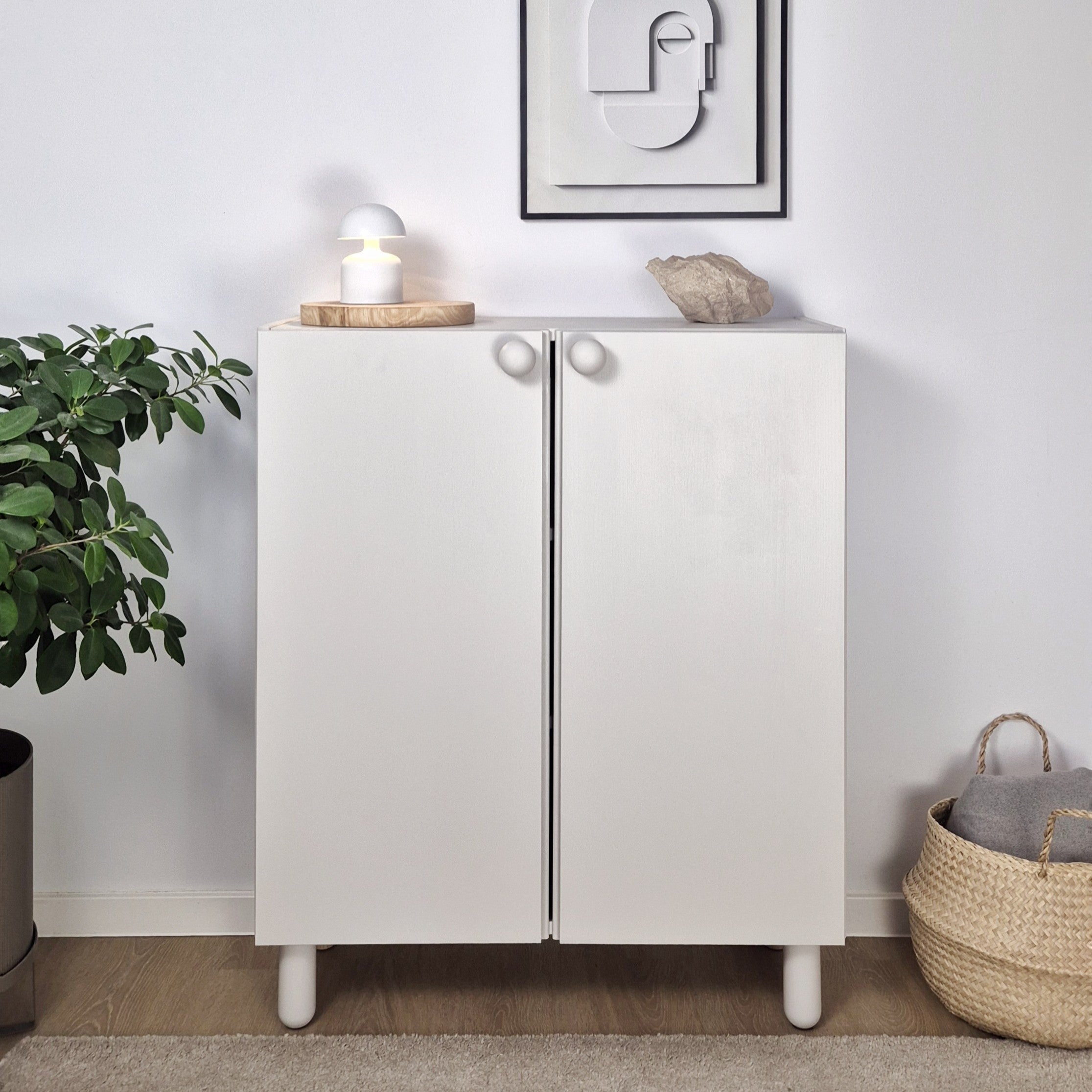 IKEA IVAR hack transformed into a stylish white cabinet with round knobs, lamp, and plant decor.