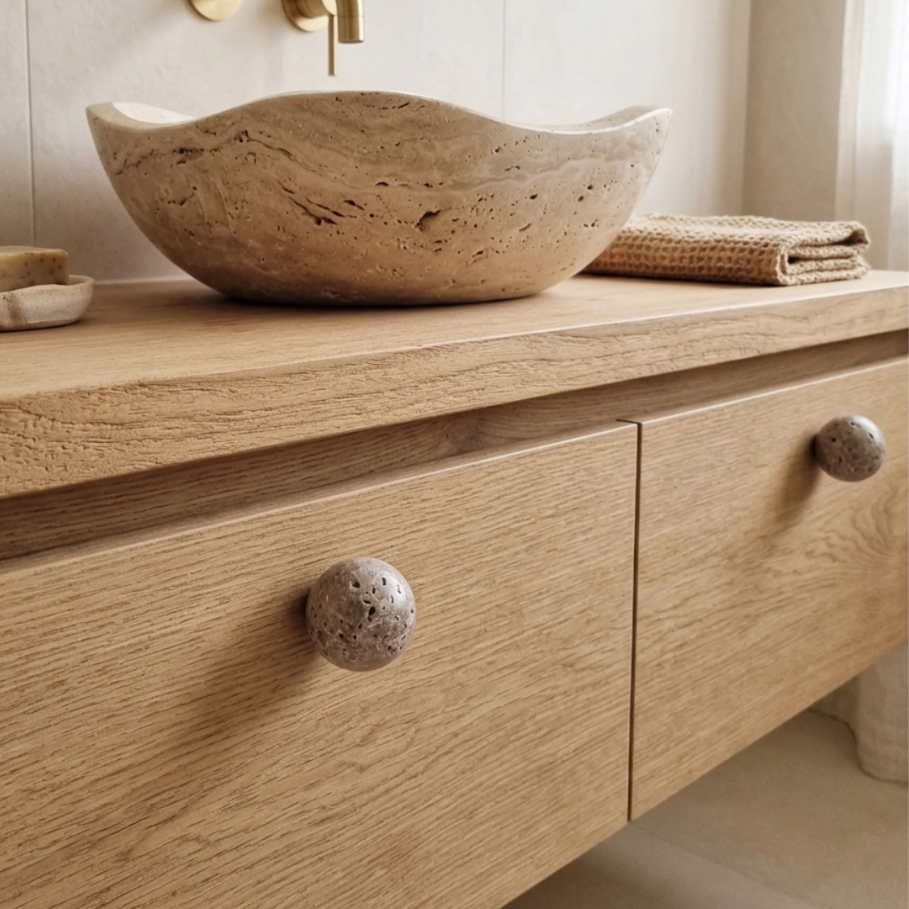 Travertine sink and travertine knobs on wooden bathroom cabinet