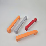 Four colorful cabinet handles on a light gray background