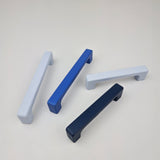 Four cabinet handles in blue, white, and navy on a light gray background