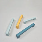Four cabinet handles in pastel colors on a light gray background