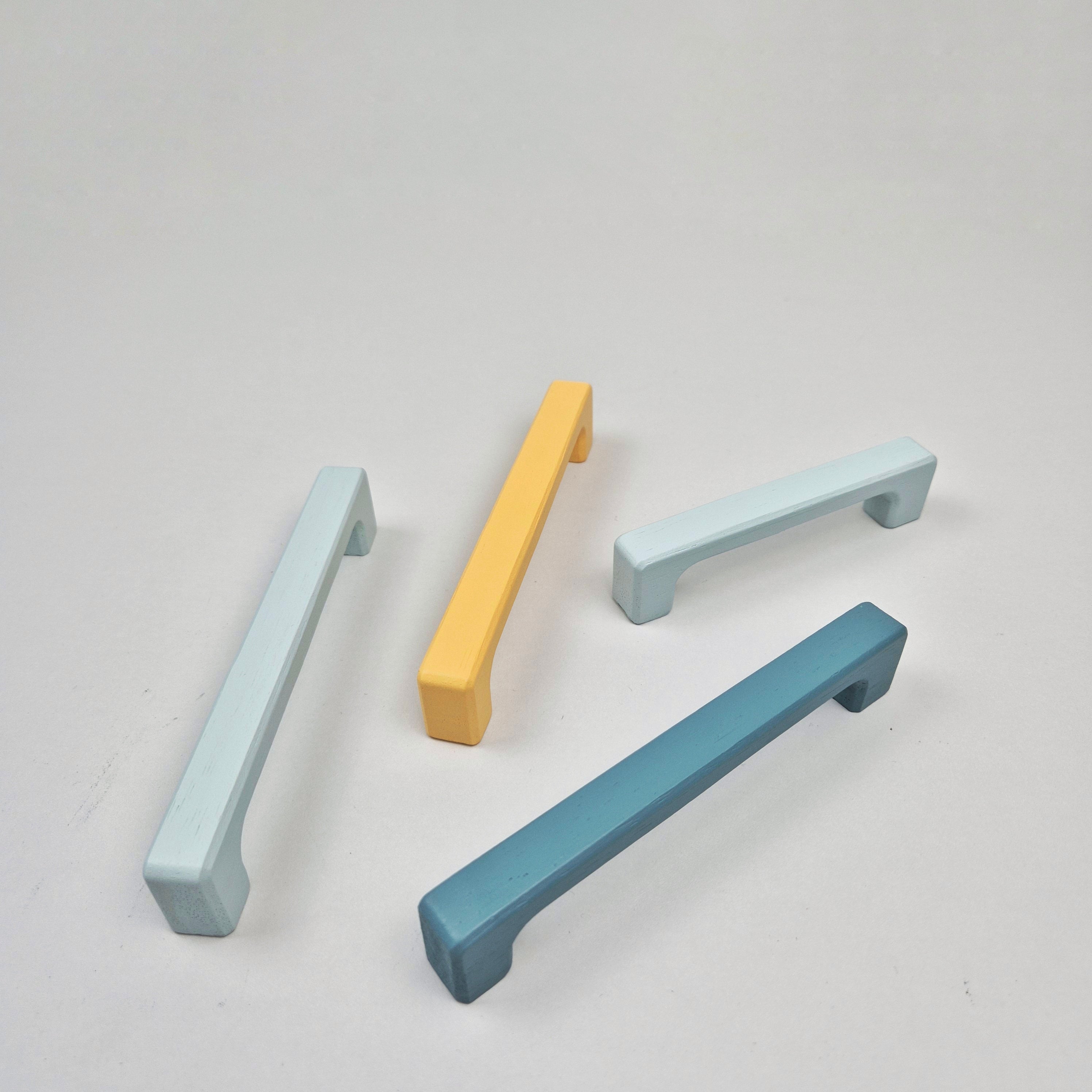 Four cabinet handles in pastel colors on a light gray background