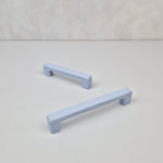 Two light blue cabinet handles on a white background