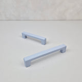 Two light blue cabinet handles on a white background
