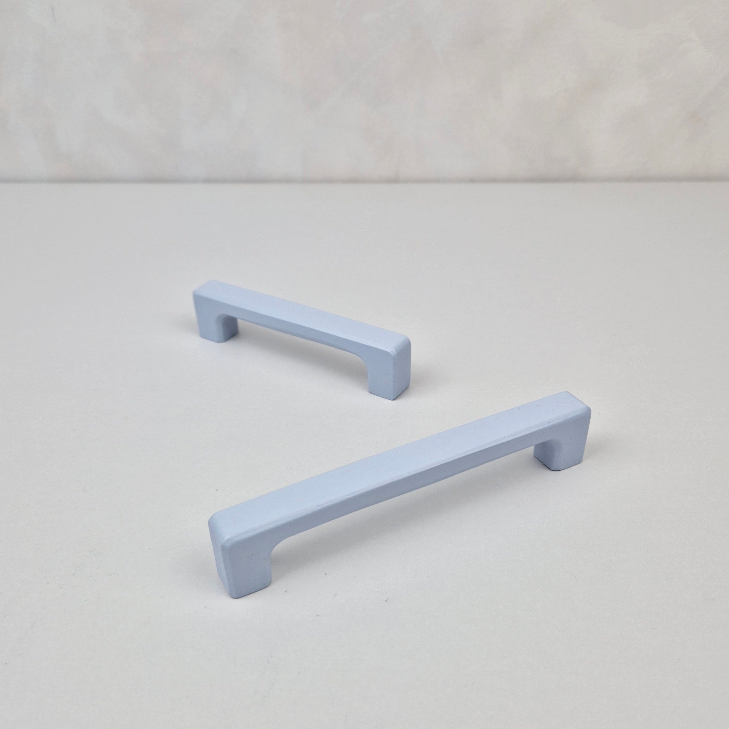 Two light blue cabinet handles on a white background