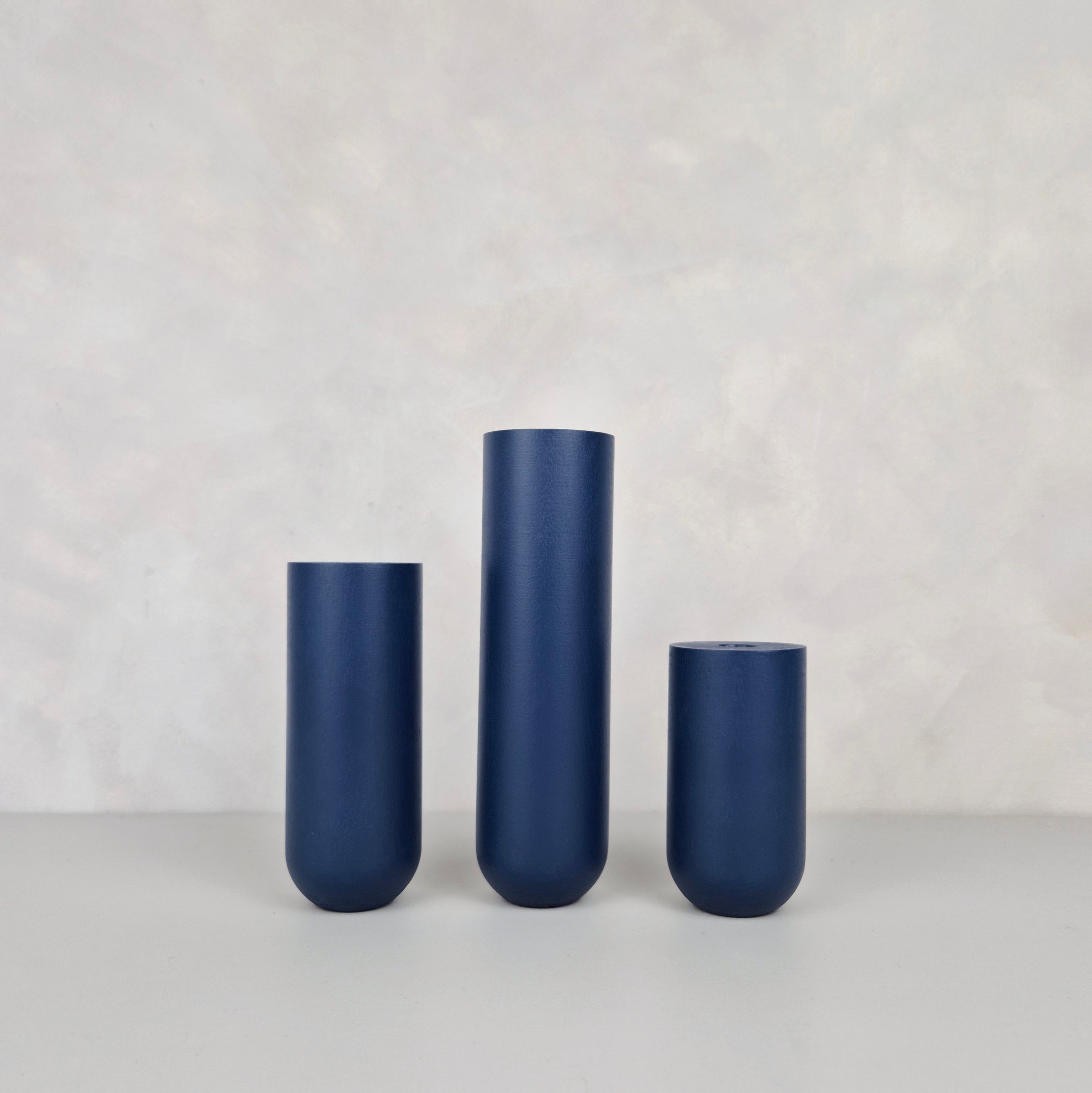 Three navy blue decorative vases of varying heights on a neutral background, perfect for home decor.