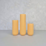 Colorful yellow ceramic vases in three sizes on a neutral background.