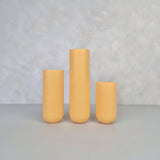 Colorful yellow ceramic vases in three sizes on a neutral background.