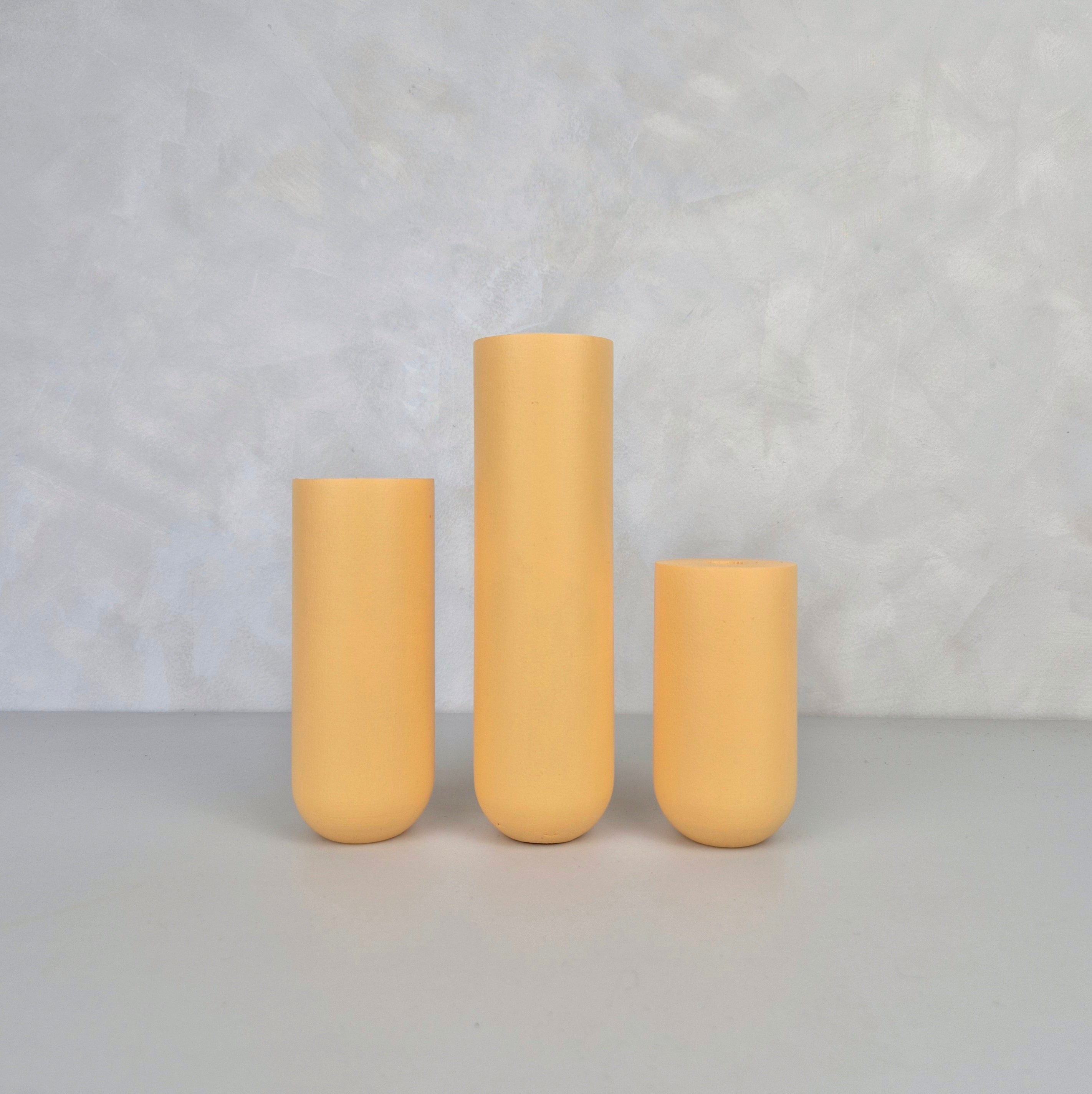 Colorful yellow ceramic vases in three sizes on a neutral background.