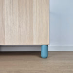 Ball furniture leg in light blue color supporting a wooden cabinet in a kids' room setting.