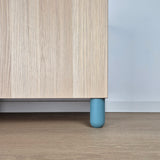 Ball furniture leg in light blue color supporting a wooden cabinet in a kids' room setting.