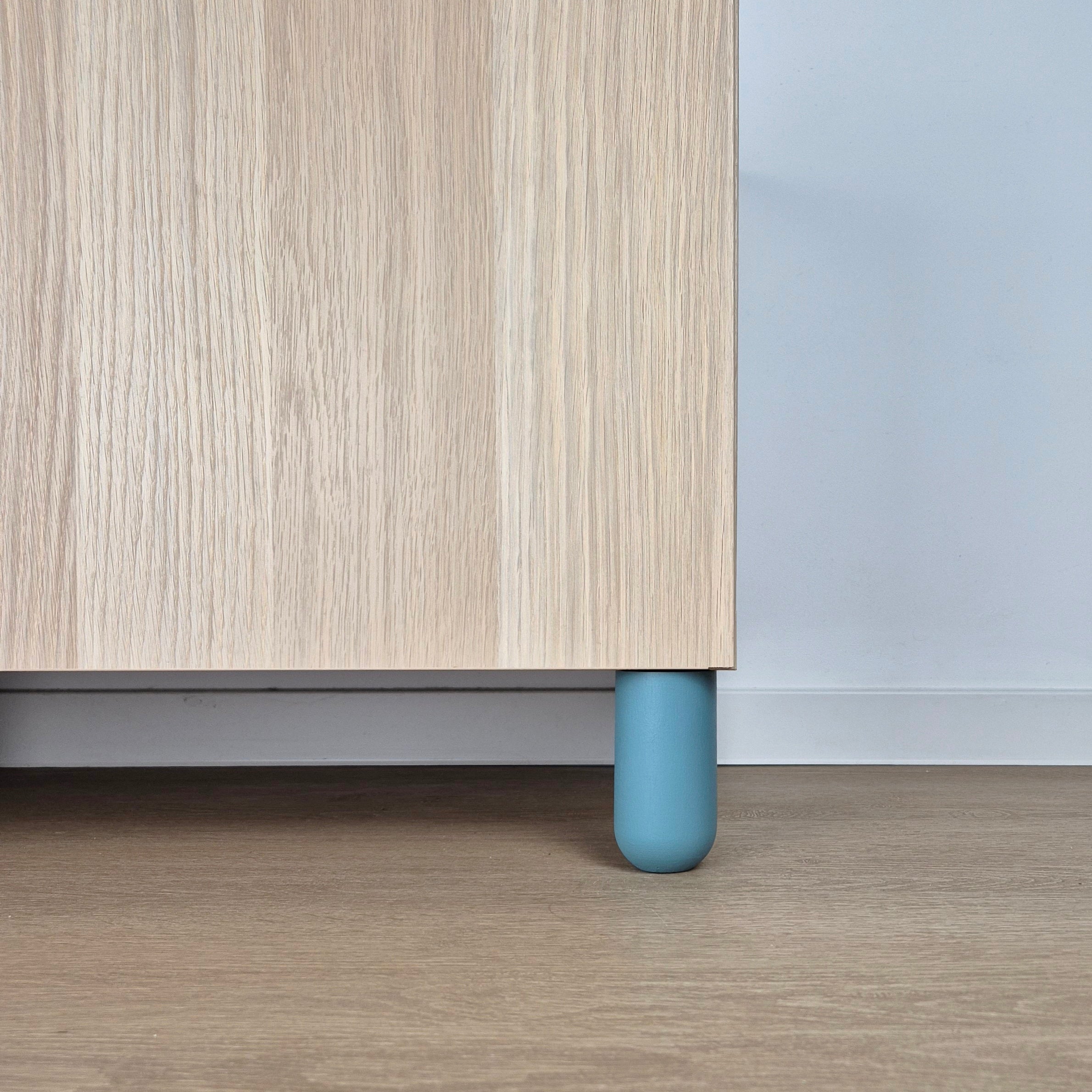 Ball furniture leg in light blue color supporting a wooden cabinet in a kids' room setting.
