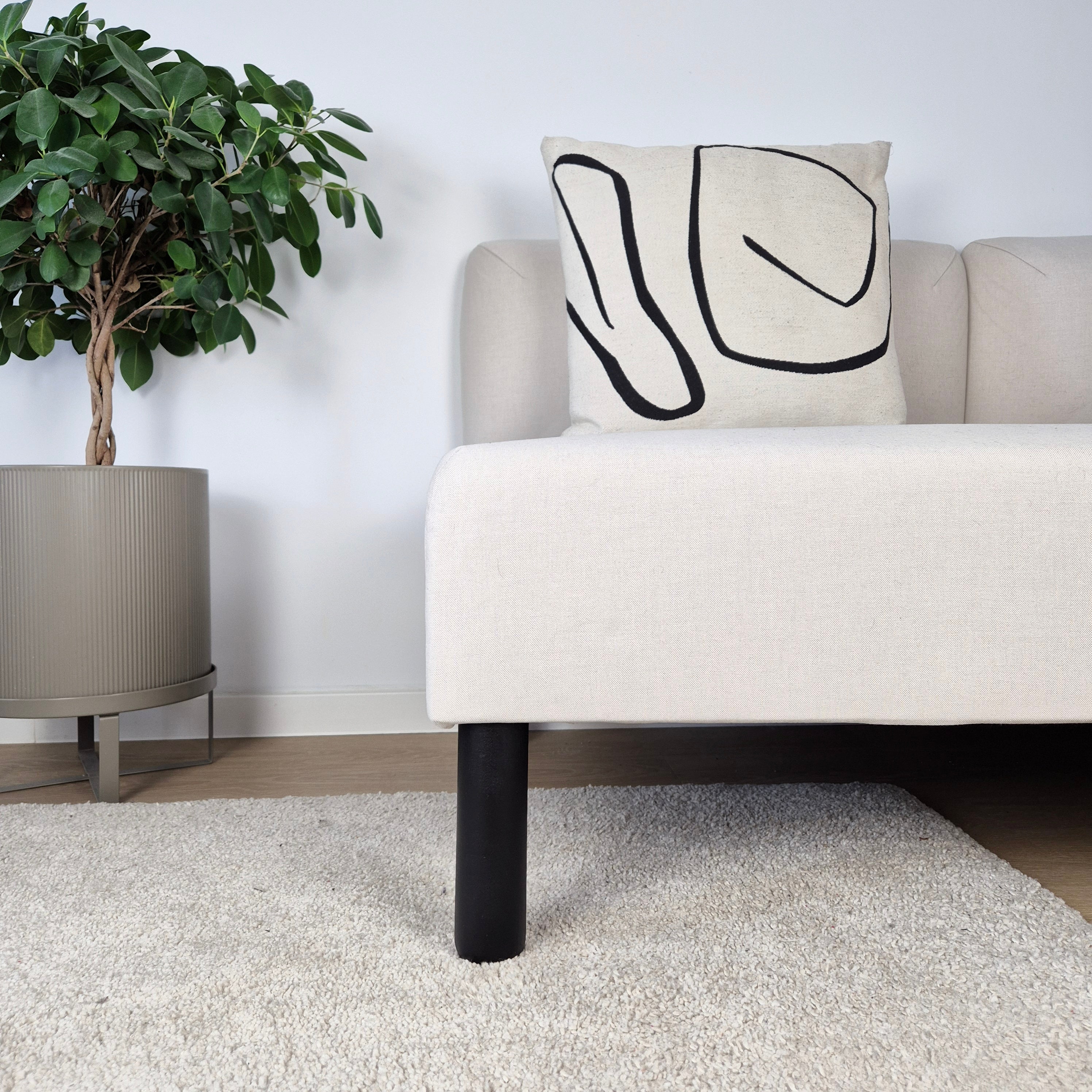 Furniture legs ARC showcased under a light sofa with a patterned cushion, featuring a wood ball furniture leg design.