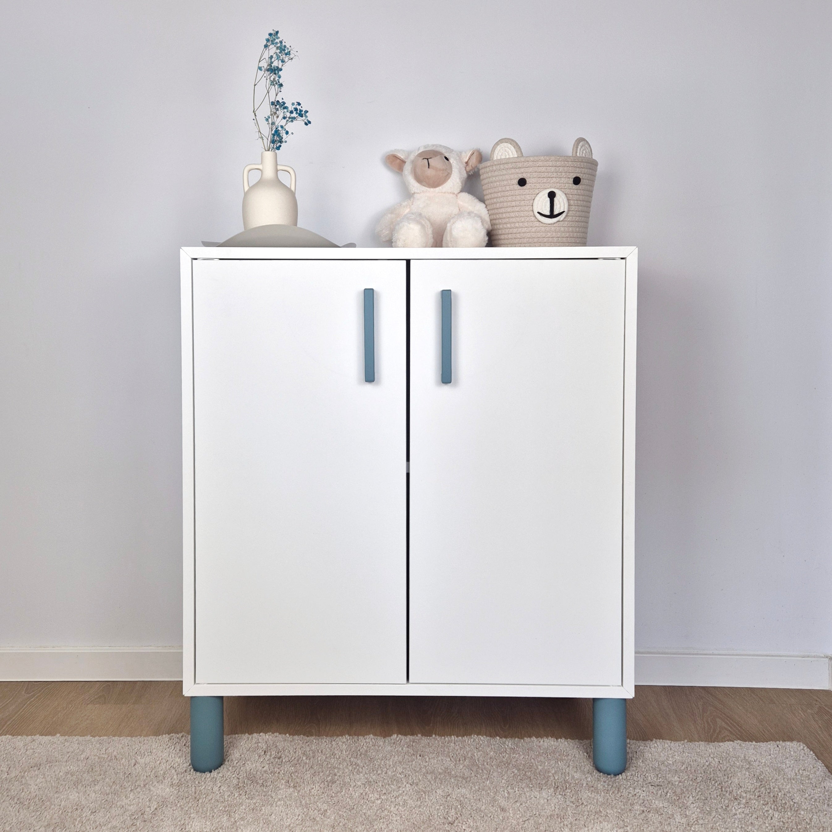 Turquoise cabinet handle on a modern white cabinet with stuffed animals and decor elements.