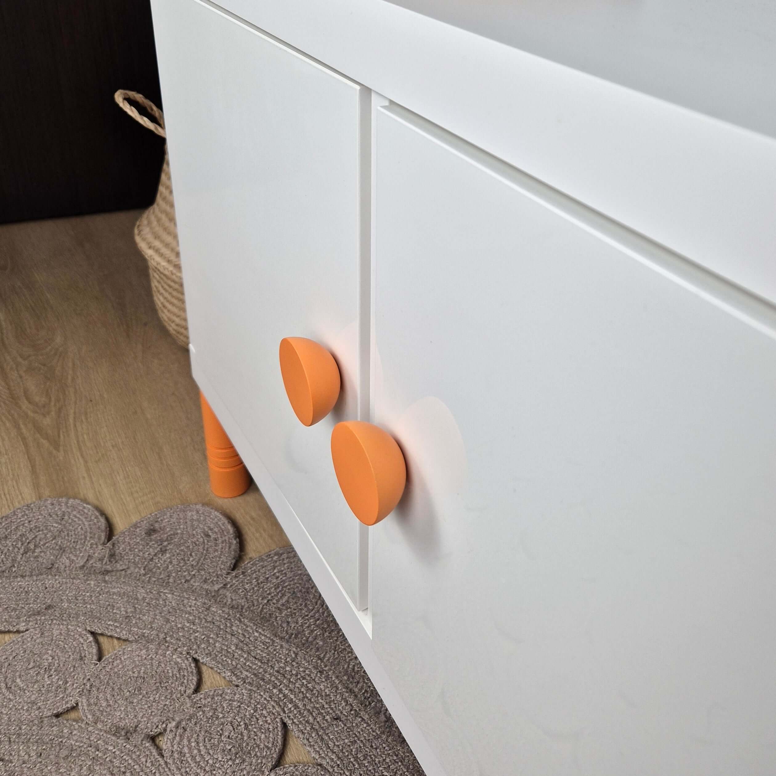 Round knob in glossy orange on a white cabinet, perfect for children's furniture accents.