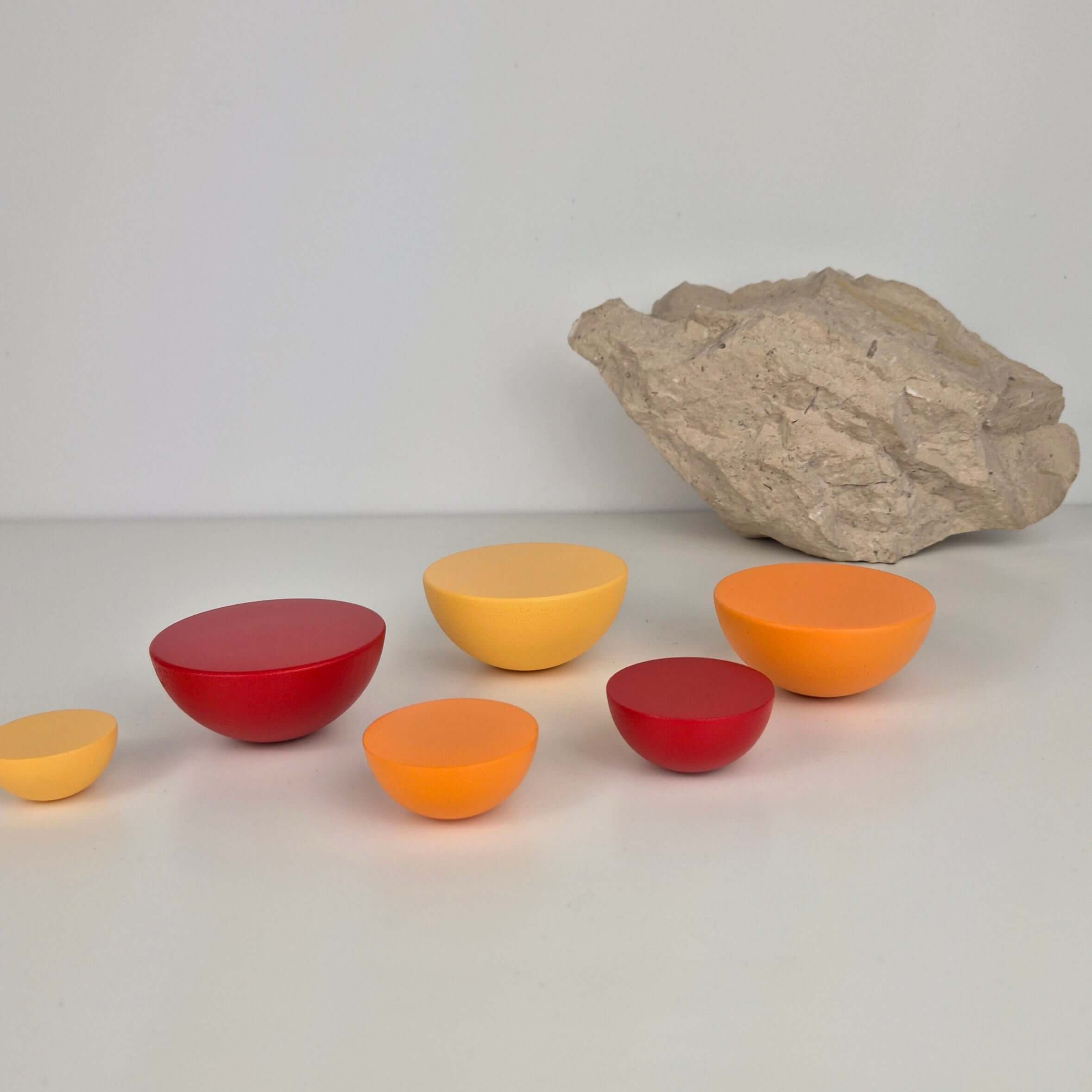 Round knob collection in vibrant colors of red, orange, and yellow with a neutral rock background.