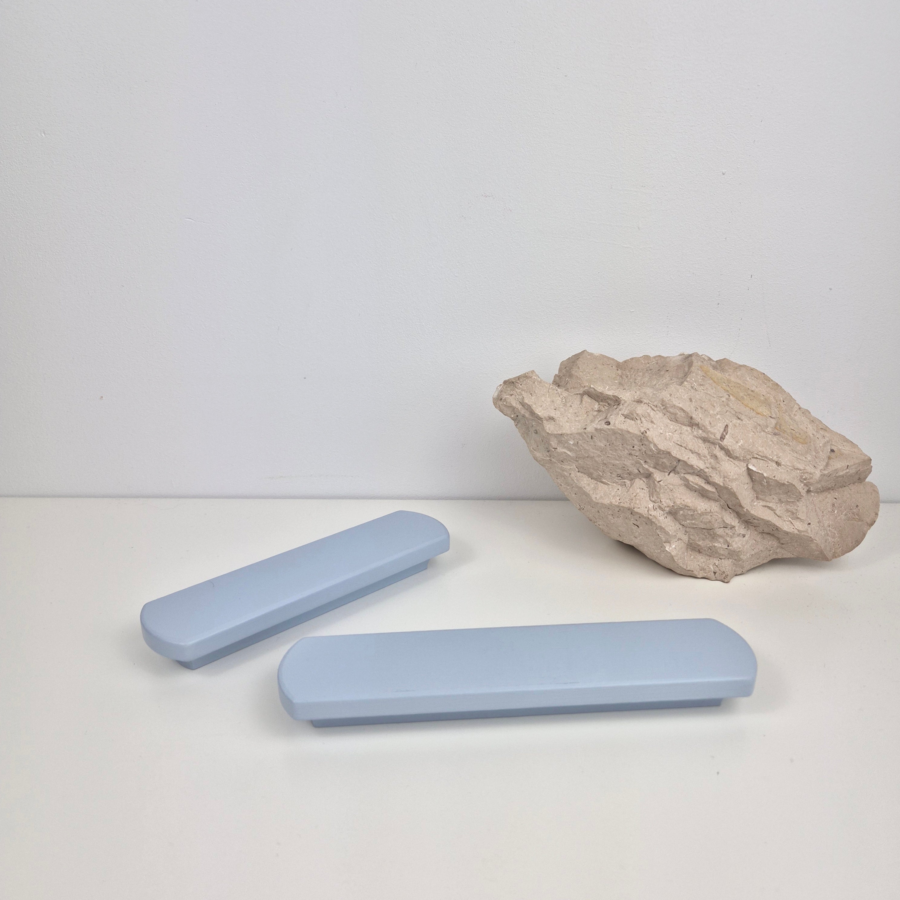 Two light blue rectangular handles and a rock on a white background