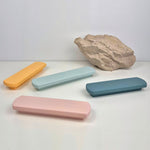 Four rectangular pastel-colored handles on a white surface with a rock in the background.