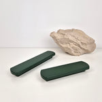 Two green rectangular handles on a white surface with a rock in the background