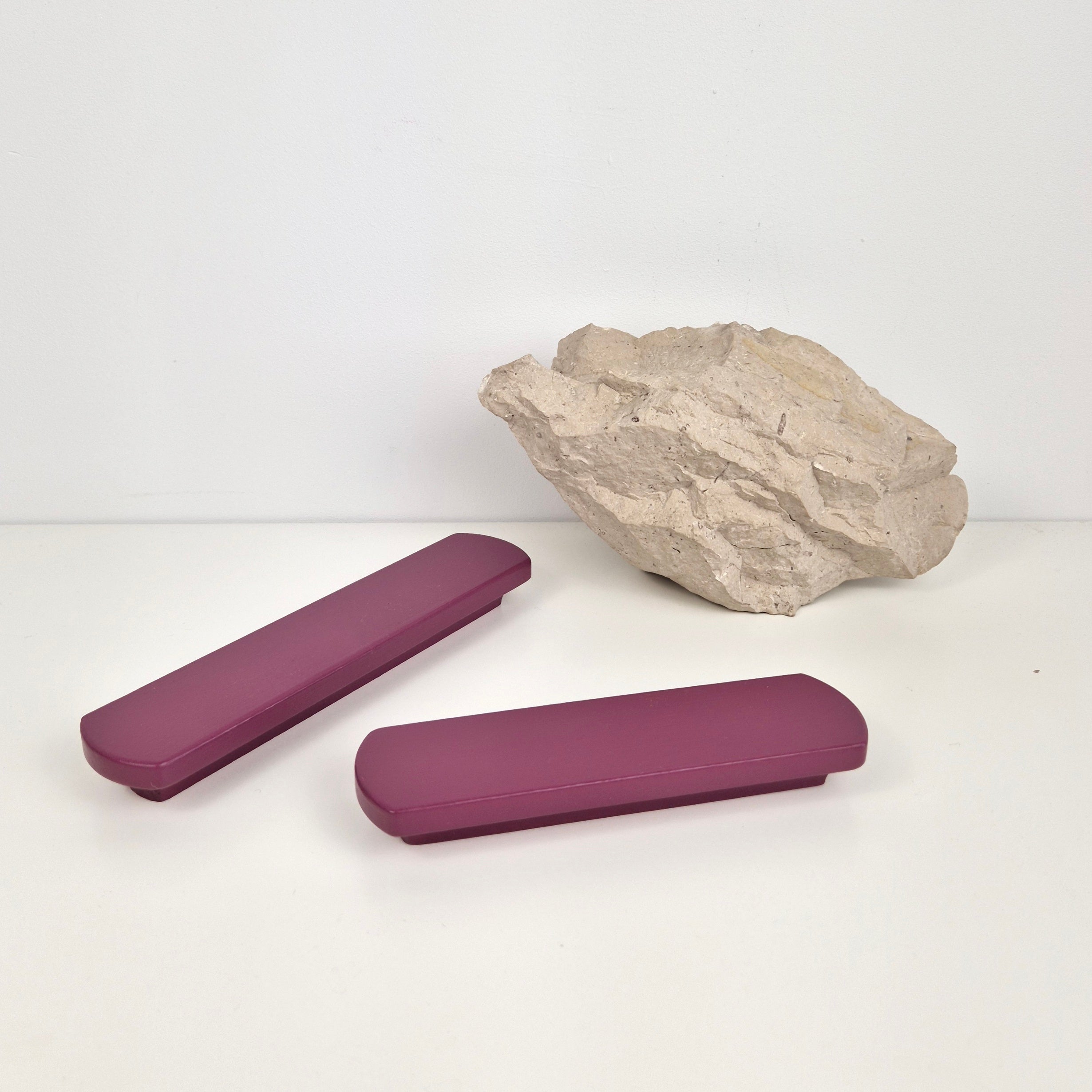 Two purple rectangular handles and a rock on a white background