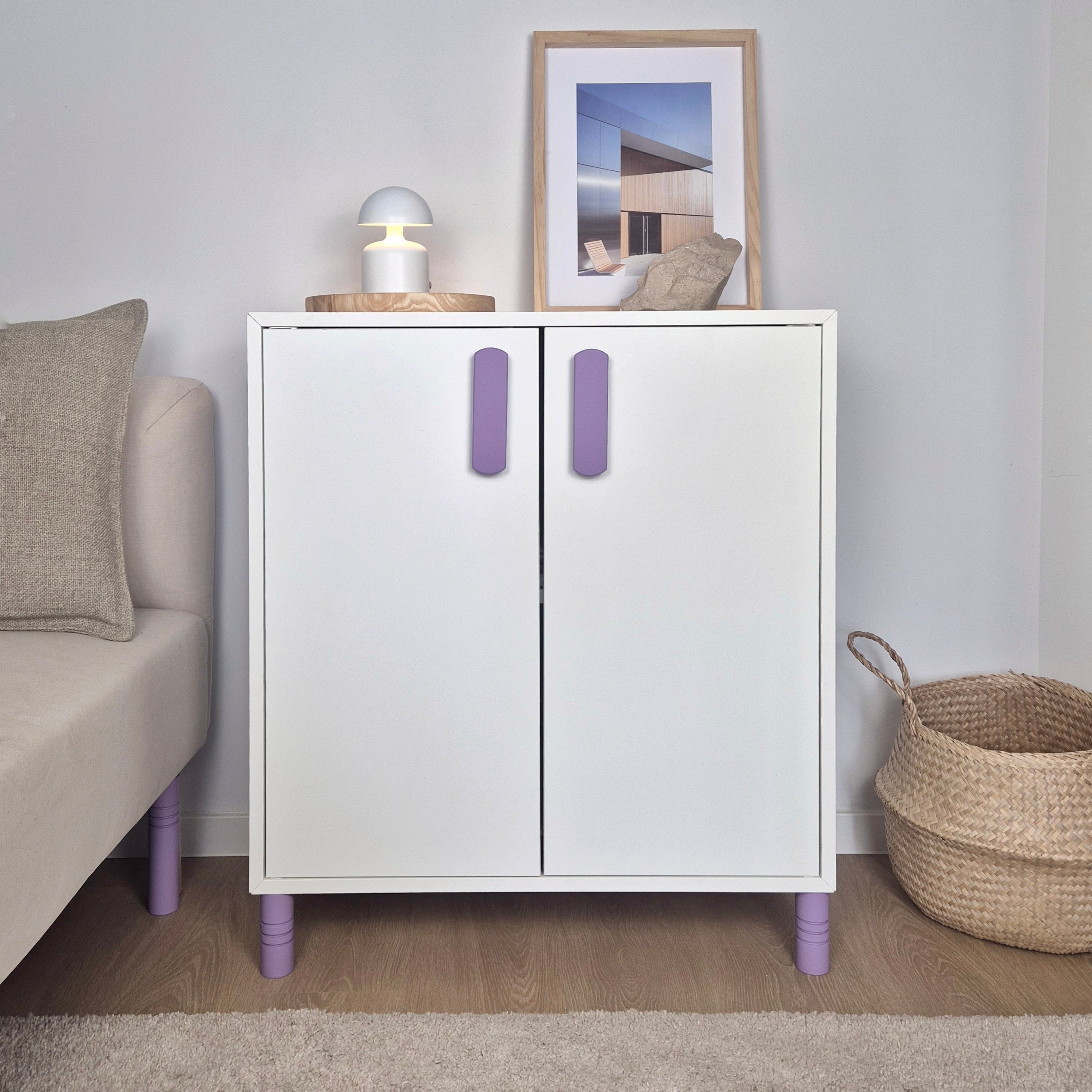 White cabinet with purple legs and handles in a room setting with a couch and basket.