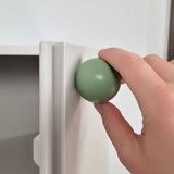 Hand turning a green knob on a white appliance.