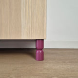 Hourglass shaped furniture legs in purple supporting a bedside table, featuring solid wood design for IKEA furniture.