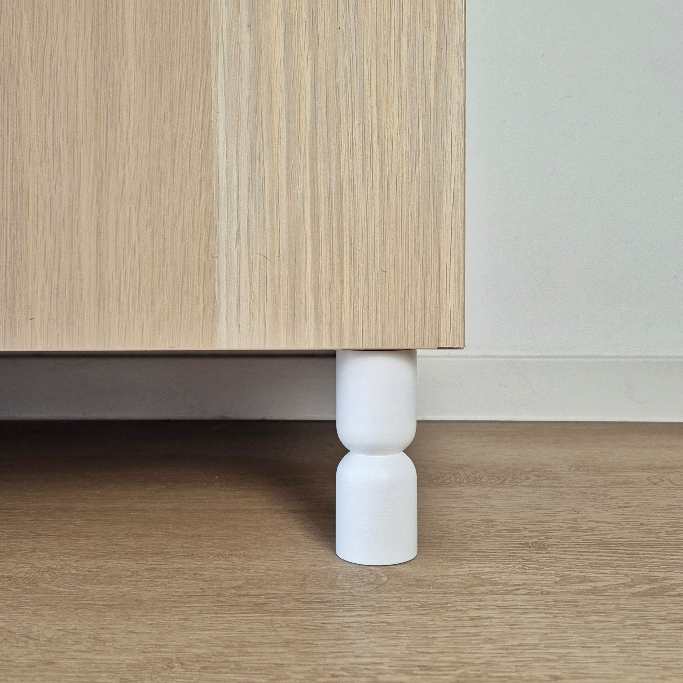 Hourglass shaped furniture legs for cabinets, designed to enhance style and support, made from solid wood in white color.