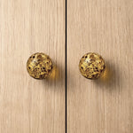 Round knob AMBER on wooden cabinet doors, showcasing luxurious amber material and modern design.