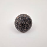 Black travertine cabinet knob close-up showing natural stone veining