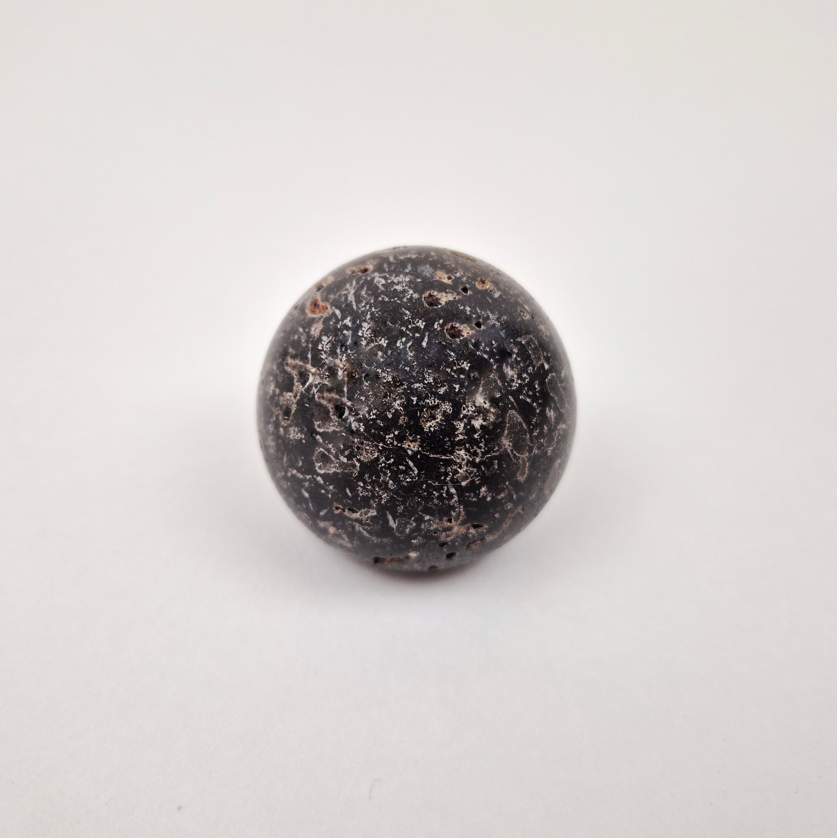 Black travertine cabinet knob close-up showing natural stone veining