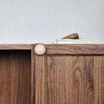 Ivory travertine cabinet knob installed on walnut cabinet door