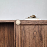 Ivory travertine cabinet knob installed on walnut cabinet door
