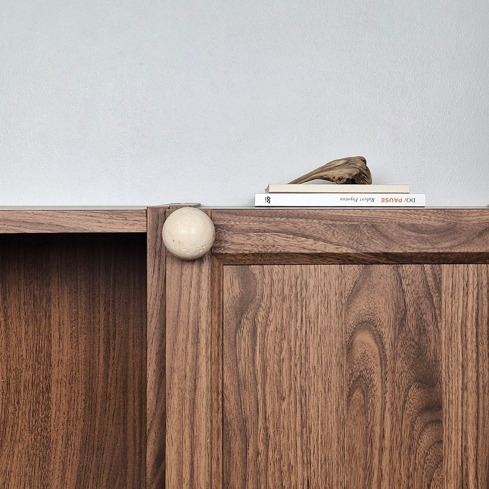Ivory travertine cabinet knob installed on walnut cabinet door