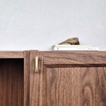 Brass cabinet pull on a wooden cabinet, showcasing modern design and warm satin finish.