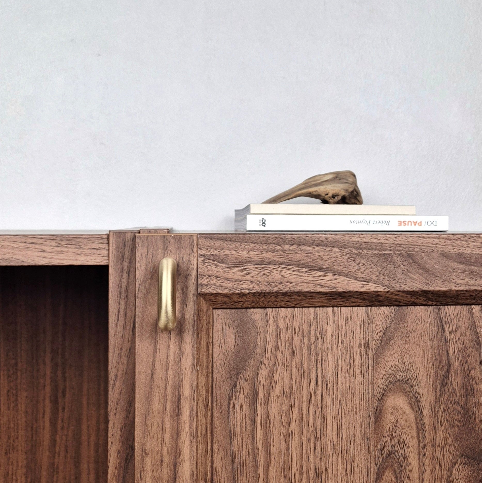 Brass cabinet pull on a wooden cabinet, showcasing modern design and warm satin finish.