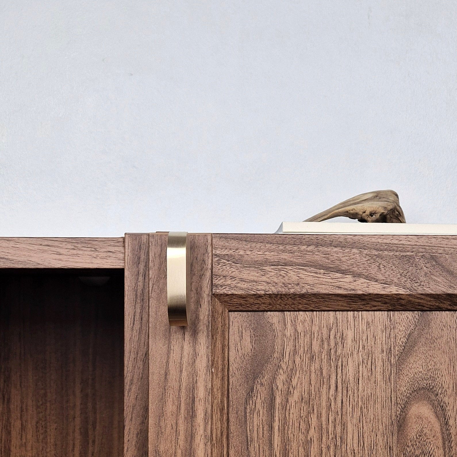 Brass cabinet pull on a wooden cabinet, adding elegance to modern furniture design.
