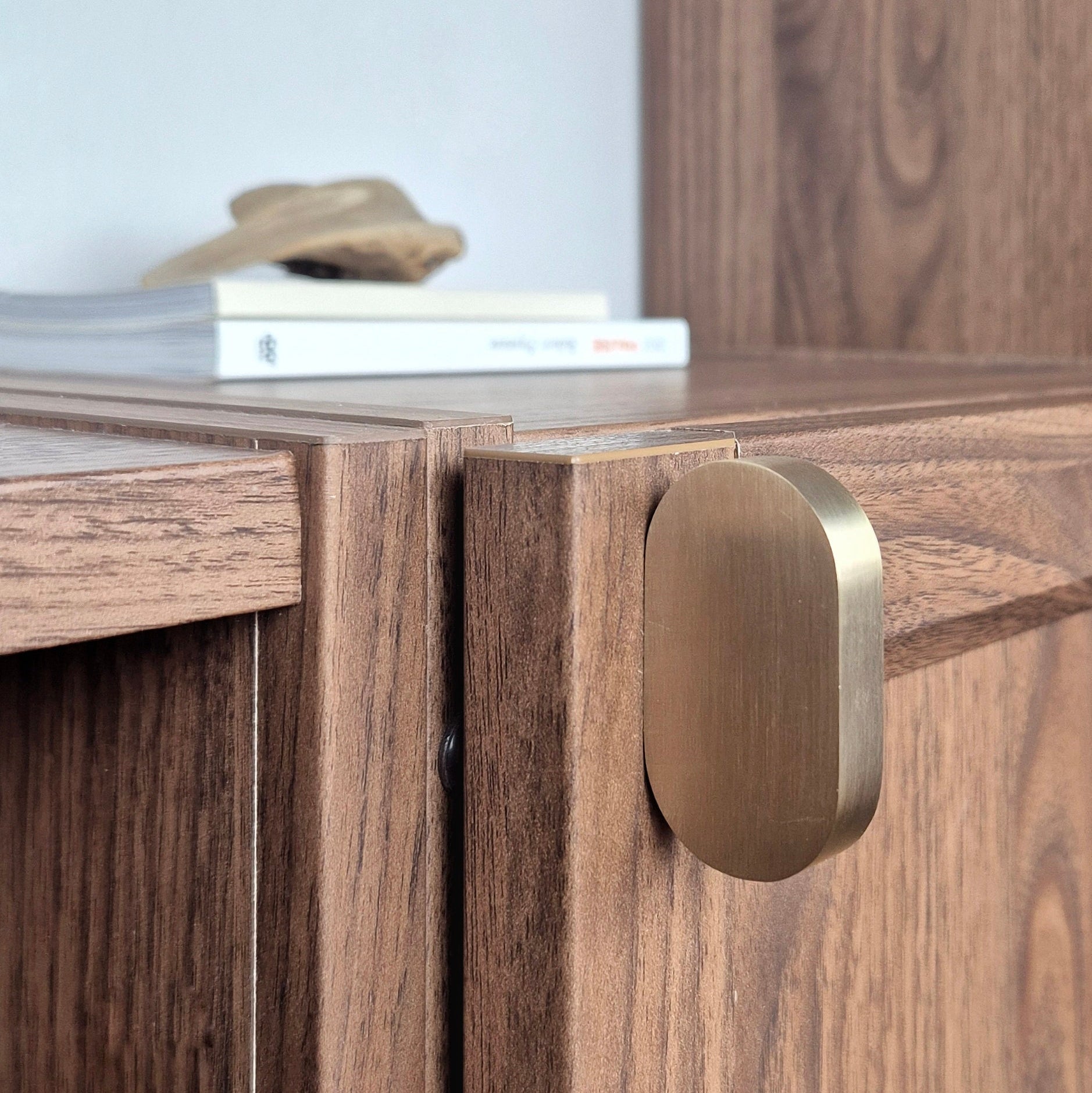 Brass cabinet pull on wooden cabinet corner, showcasing unique design and warm satin finish for stylish home decor.