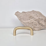 Brass cabinet pull DOME showcased with a natural stone background on a minimalist surface.