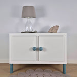 View of a stylish bedside table with striped furniture legs, a lamp, and decorative stone on top.