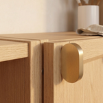 Brass cabinet pull mounted on a wooden cabinet, showcasing its elegant design and warm satin finish.
